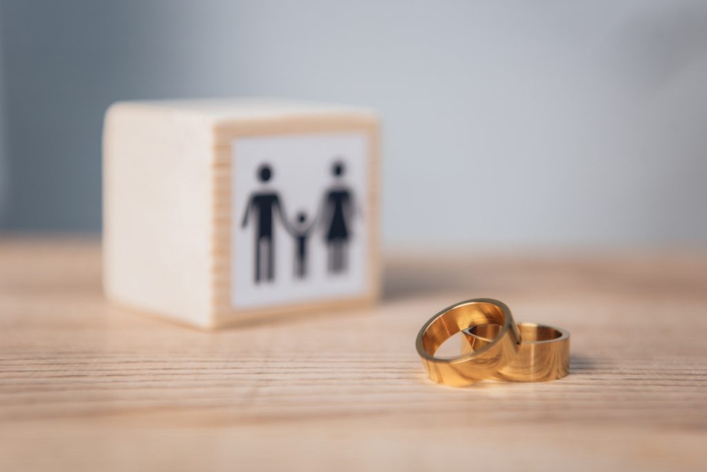 Selective Focus Of Golden Rings Near Wooden Cube With Family