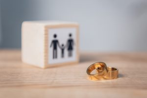 Selective Focus Of Golden Rings Near Wooden Cube With Family